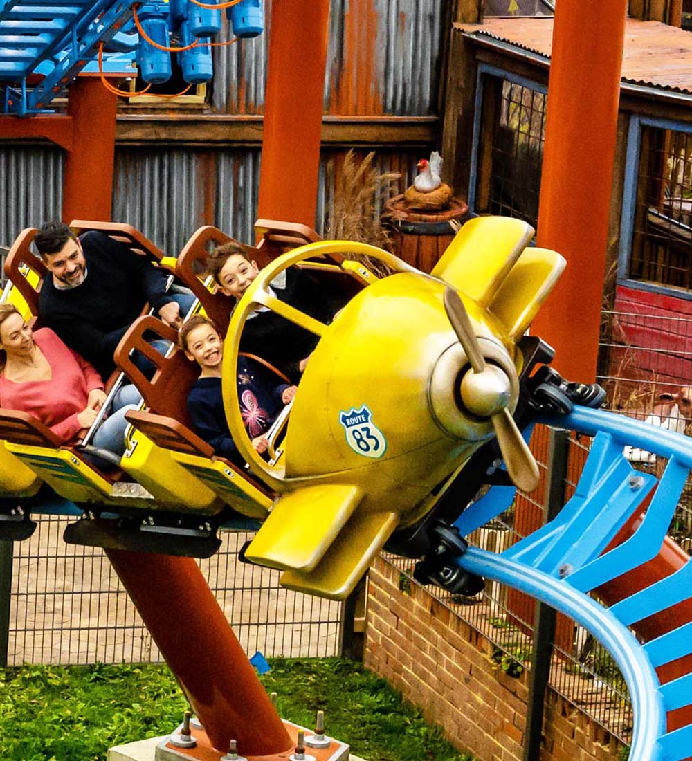 Family riding the Farmyard Flyer plane ride in Tornado Springs at Paultons Park