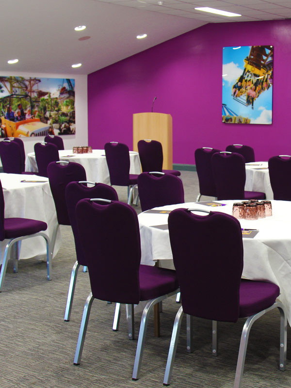 Corporate event room set up with round tables and purple chairs at Paultons Park