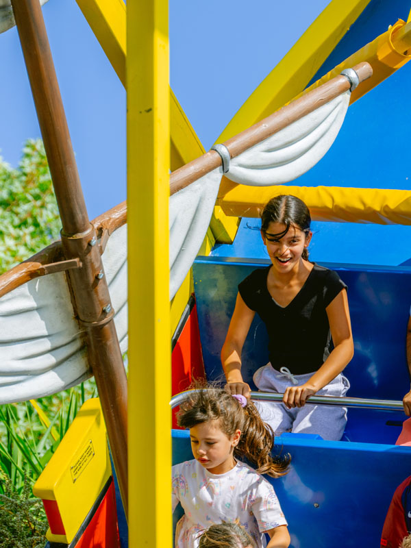 Children smiling on the Pirate Ship ride at Paultons Park as the boat swings through the air