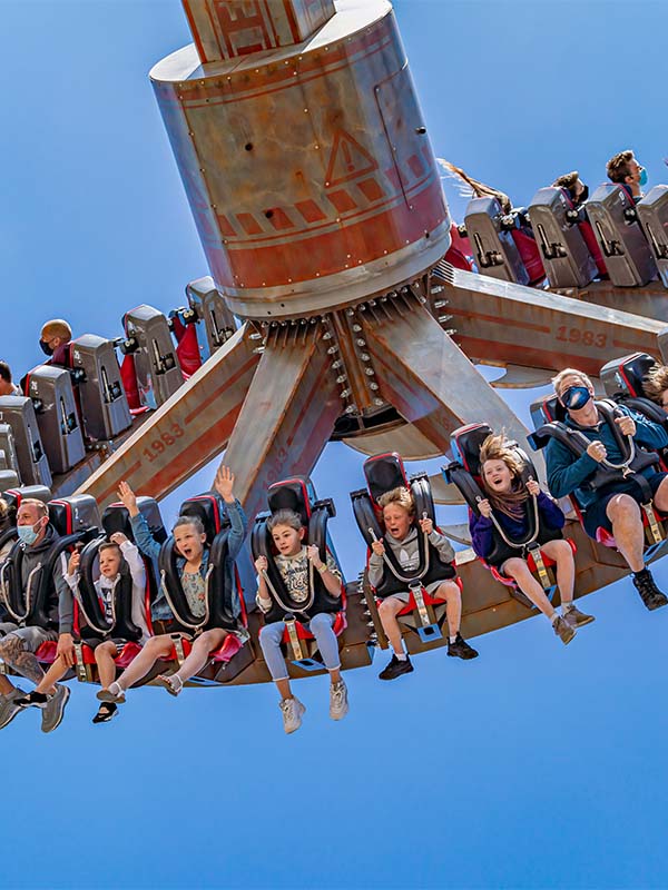 Cyclonator at Paultons Park spinning high above the ground with riders inverted against a clear blue sky