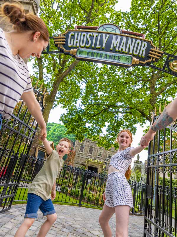 Children entering Ghostly Manor attraction at Paultons Park beneath themed entrance sign