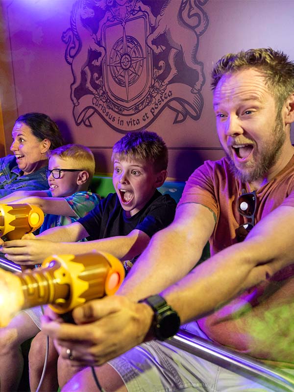 Family laughing and aiming laser blasters on Ghostly Manor dark ride at Paultons Park