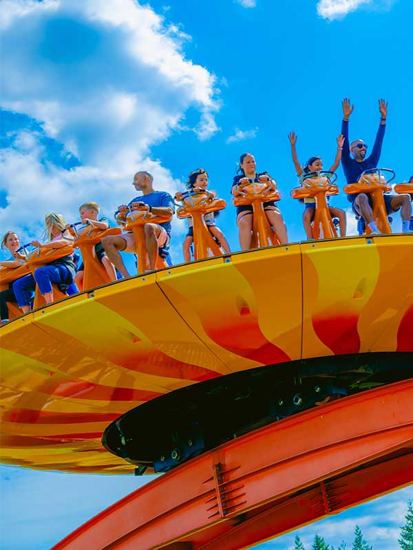 Guests riding EDGE at Paultons Park as the giant spinning disc tilts high into the sky on a sunny day