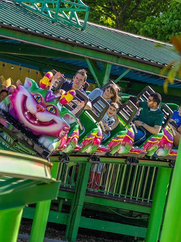 Family riding the Cat-O-Pillar Coaster at Paultons Park as the colourful caterpillar train curves along the green track