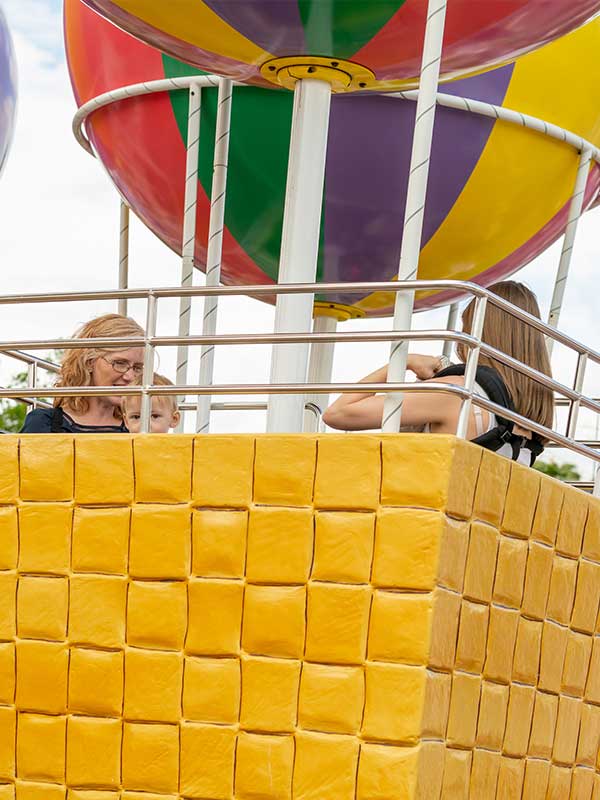 Peppa’s Big Balloon Ride hot air balloons rising above Peppa Pig World at Paultons Park with colourful striped balloons and yellow baskets