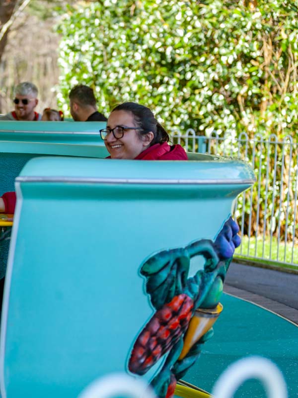 Guest smiling while riding the Tea Cup Ride at Paultons Park in a pastel green teacup
