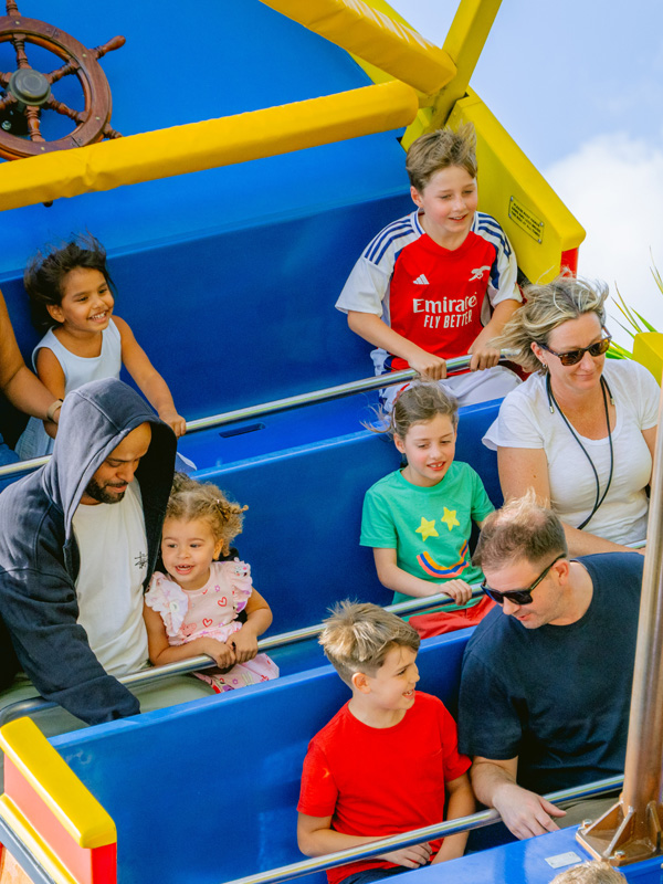 Children smiling on the Pirate Ship ride at Paultons Park as the boat swings through the air