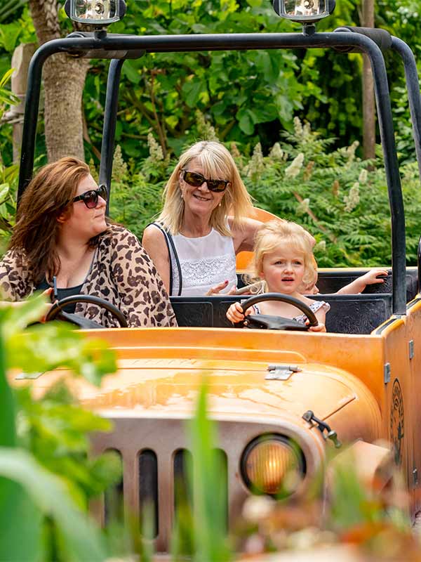 Mother and child driving Dino Tour Co jeep through jungle scenery at Paultons Park