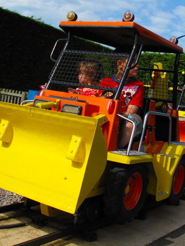 Children driving bright yellow and orange construction trucks on the Digger Ride at Paultons Park