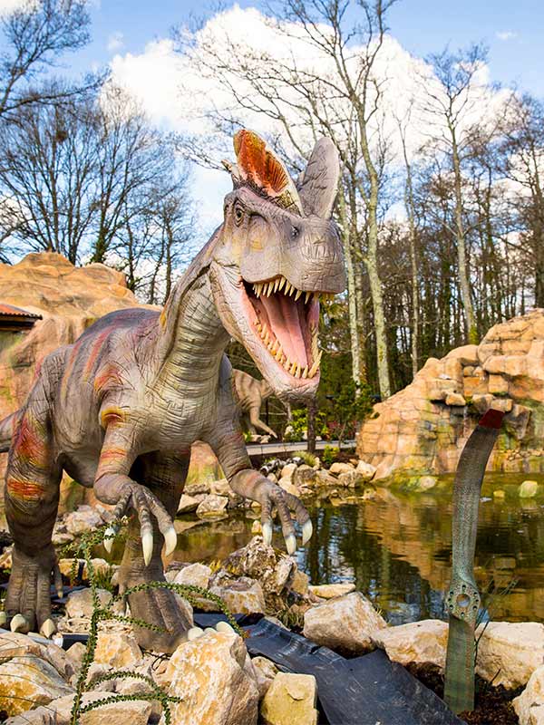 Dinosaur statue roaring beside water on Dino Tour Co ride at Paultons Park