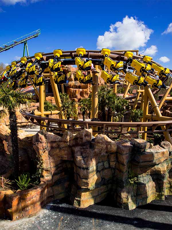 Flight of the Pterosaur roller coaster at Paultons Park flying above rocky dinosaur themed landscape on a bright sunny day
