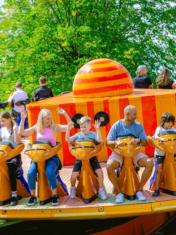 Families enjoying EDGE at Paultons Park seated on the colourful rotating disc ride