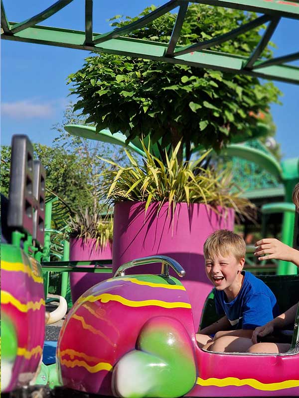 Young boy laughing on the Cat-O-Pillar Coaster at Paultons Park in a brightly coloured caterpillar car