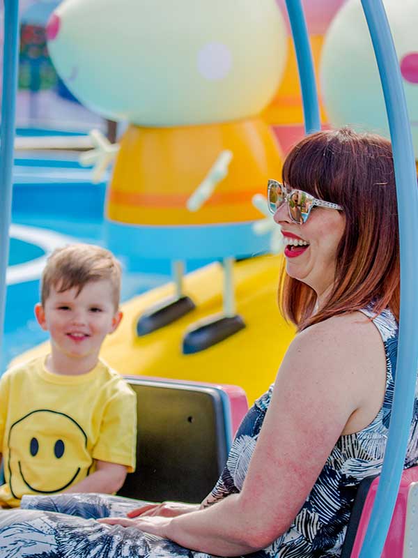 Mother and son smiling on Grampy Rabbit’s Sailing Club ride in Peppa Pig World at Paultons Park