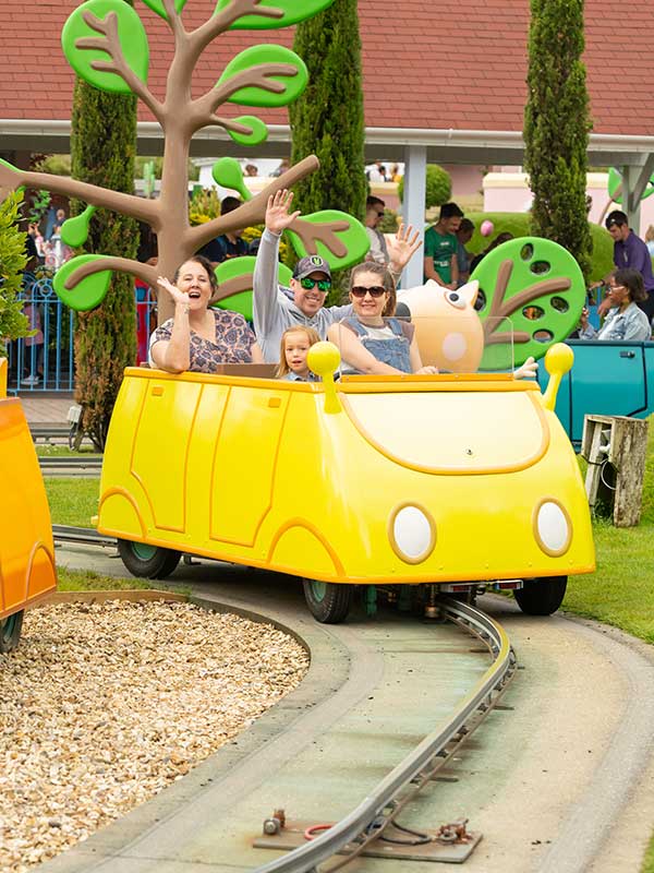Family riding Daddy Pig’s Car Ride in Peppa Pig World at Paultons Park in a pink car