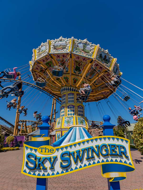 The Sky Swinger sign in front of the spinning swing ride at Paultons Park