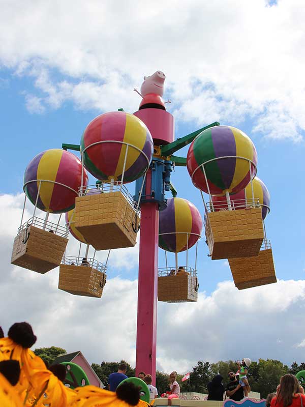 Children riding in a Peppa’s Big Balloon Ride basket with bright striped balloon above at Peppa Pig World Paultons Park