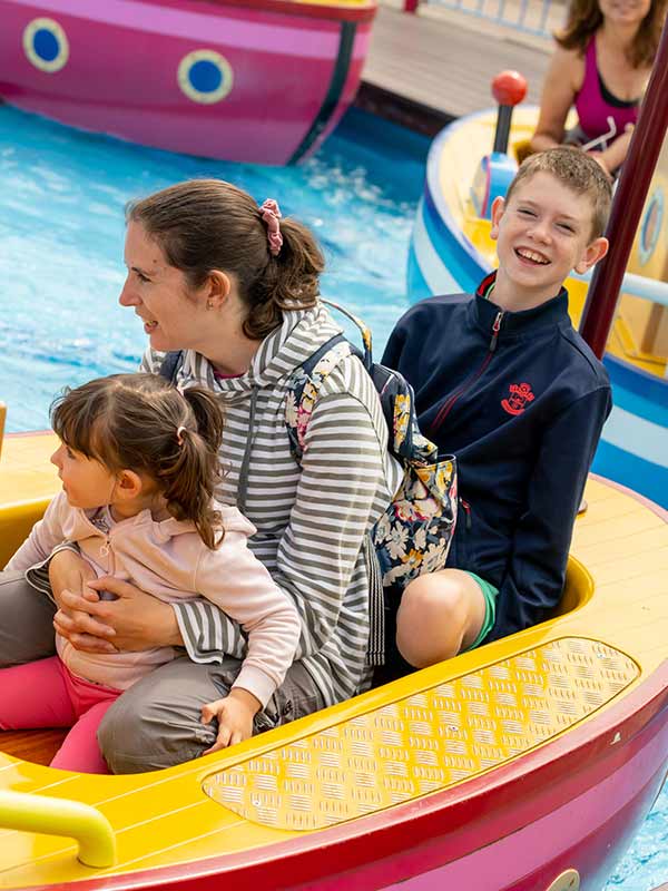 Mother and children smiling while riding Grandpa Pig’s Boat Trip in Peppa Pig World at Paultons Park