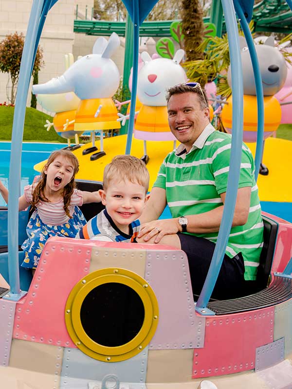 Father and children riding Grampy Rabbit’s Sailing Club boats in Peppa Pig World at Paultons Park