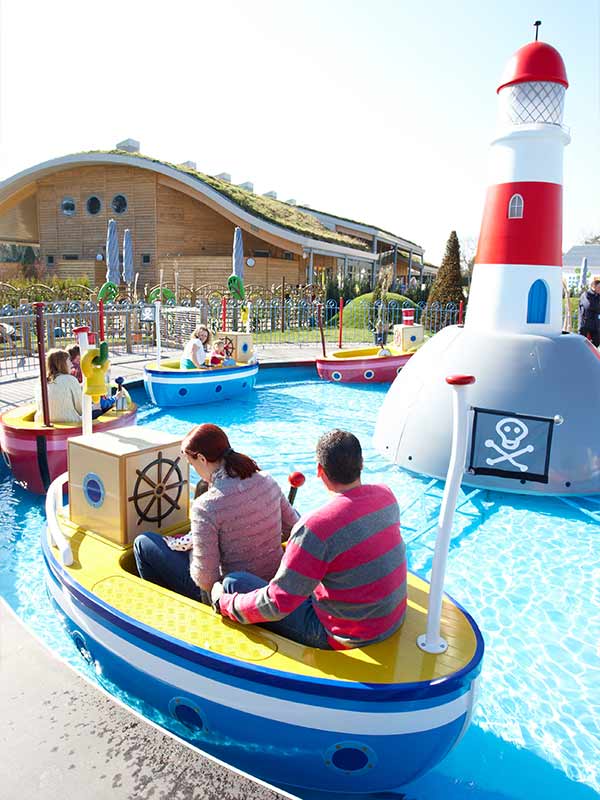 Colourful boats sailing around lighthouse on Grandpa Pig’s Boat Trip in Peppa Pig World at Paultons Park