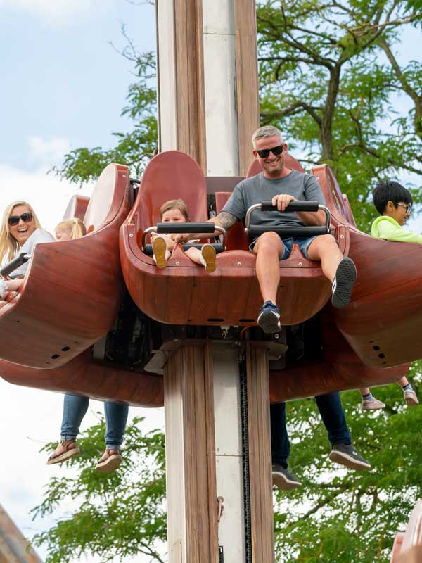 Family enjoying the Windmill Towers drop ride at Paultons Park with windmill theming and blue sky