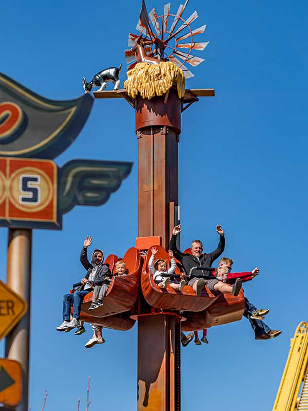 Children and adults riding Windmill Towers at Paultons Park with hands raised on the family drop tower