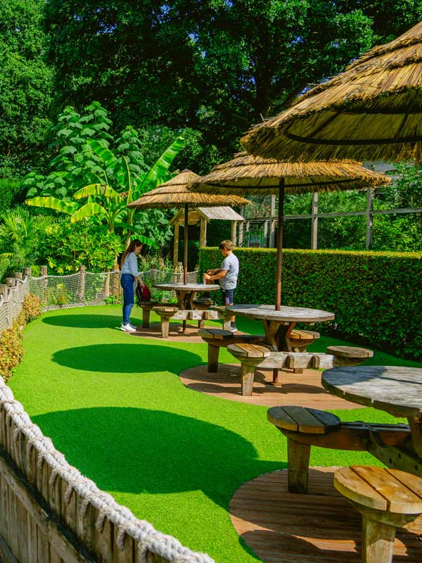 Close up of carved tiki totem in African Gardens at Paultons Park surrounded by plants and wooden fencing