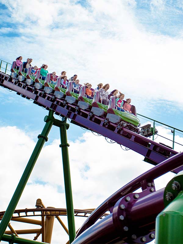 Riders cresting the track on the Velociraptor roller coaster at Paultons Park against a bright blue sky