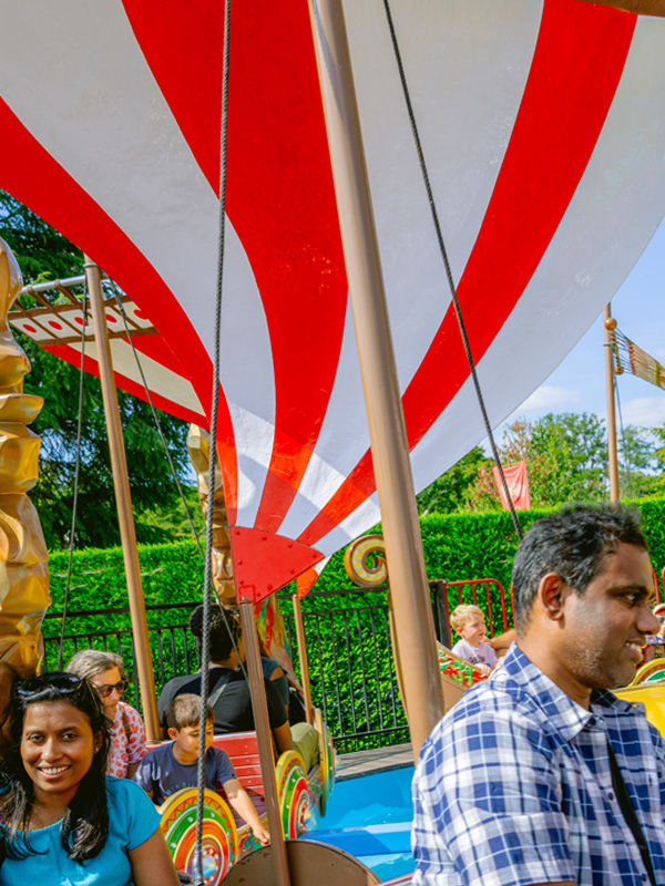 Family seated in Viking Boats spinning ride under red and white sails at Paultons Park