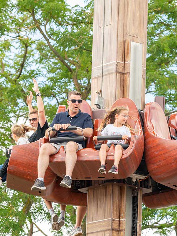 Guests smiling on Windmill Towers drop tower ride at Paultons Park surrounded by trees