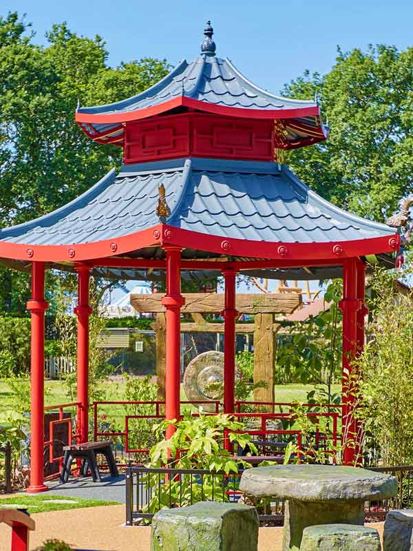 Red pagoda gazebo in the Japanese Garden at Paultons Park surrounded by landscaped greenery and stone features