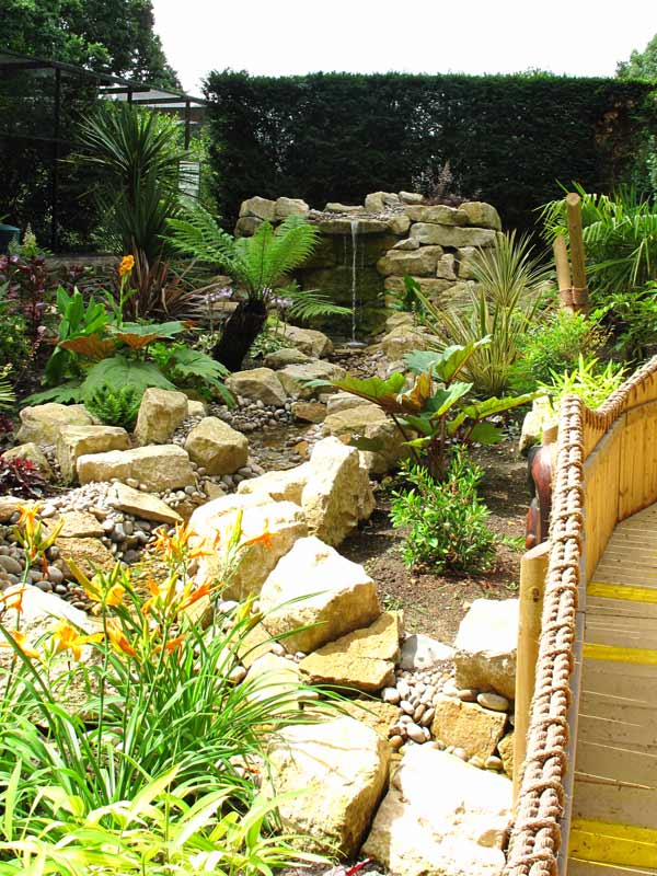 Crocodile-shaped topiary beside a pond in Jungle Falls Garden at Paultons Park