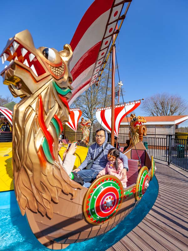 Father and daughter riding Viking Boats with dragon figurehead at Paultons Park