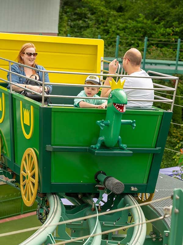Child and parents waving from The Queen’s Flying Coach Ride in Peppa Pig World at Paultons Park