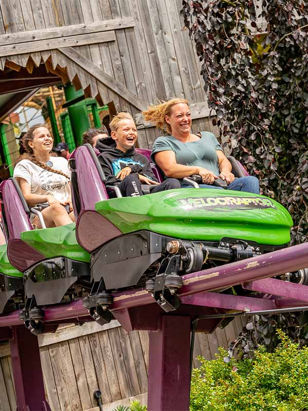 Family enjoying the Velociraptor roller coaster at Paultons Park as the train speeds along the purple track