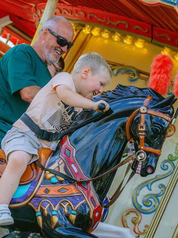 Young child riding a painted carousel horse on the Victorian Carousel at Paultons Park