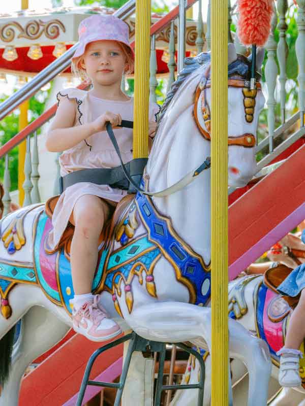 Girl riding a white carousel horse on the Victorian Carousel Ride at Paultons Park