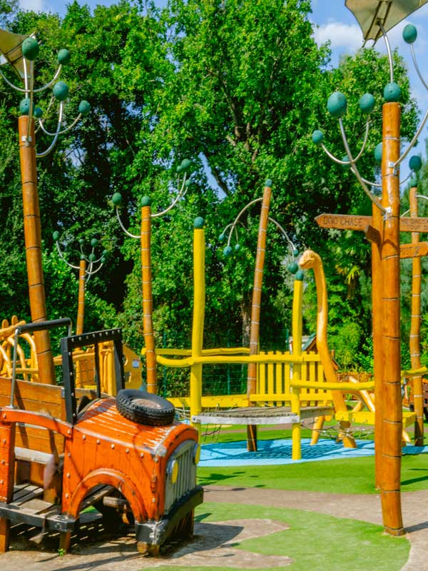 Dinosaur-themed climbing area at Little Explorers Playground in Paultons Park with wooden structures and greenery