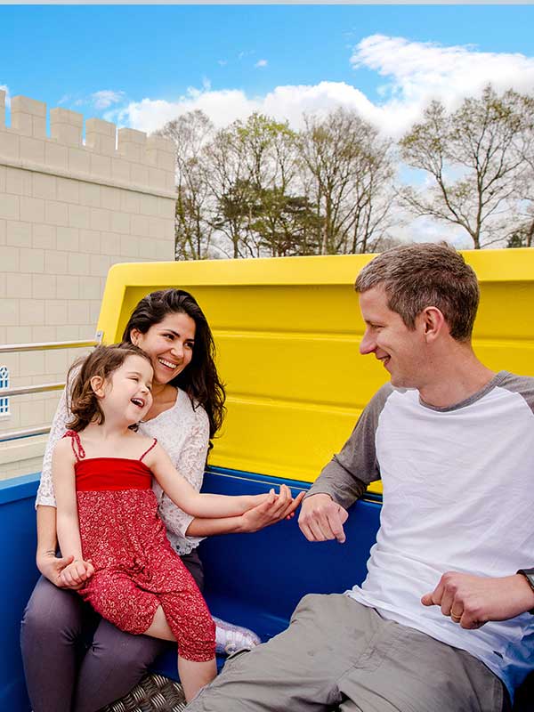 Family riding colourful royal carriage on The Queen’s Flying Coach Ride in Peppa Pig World at Paultons Park