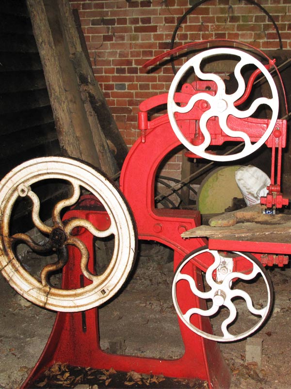 Large black working water wheel beside brick mill building at The Watermill in Paultons Park