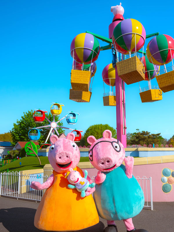 Peppa Pig and Daddy Pig with Baby Evie Pig near the colourful balloon ride in Peppa Pig World at Paultons Park