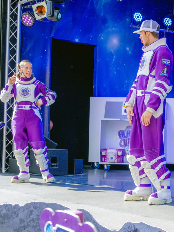 Live actors in purple space costumes performing in the Blast Off Summer Show at Paultons Park