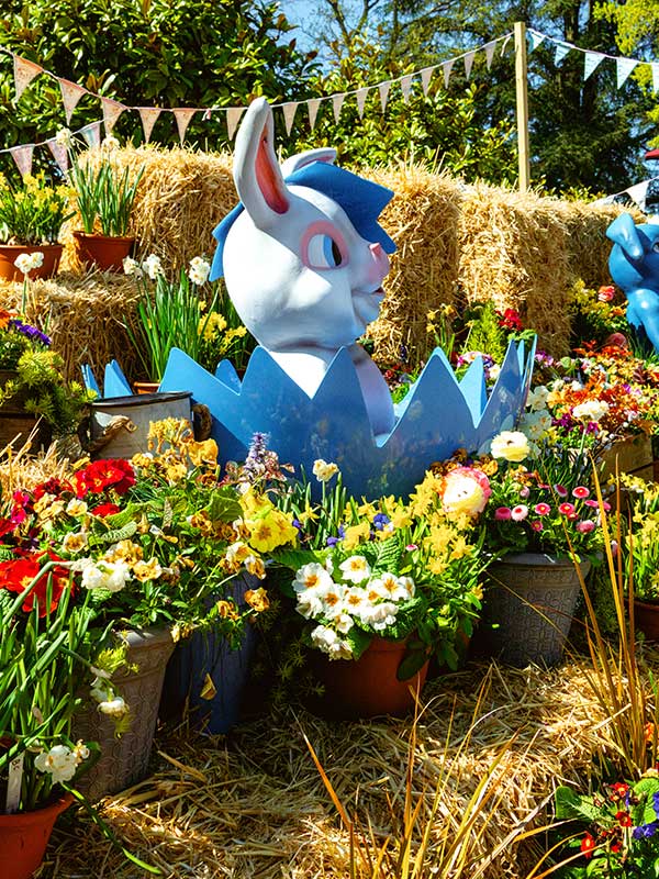 Easter garden display at Paultons Park with bunny figure in decorative egg surrounded by colourful spring flowers