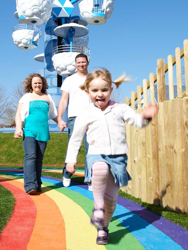 Young child running out of red tunnel slide at Mr Potato's Playground in Peppa Pig World at Paultons Park