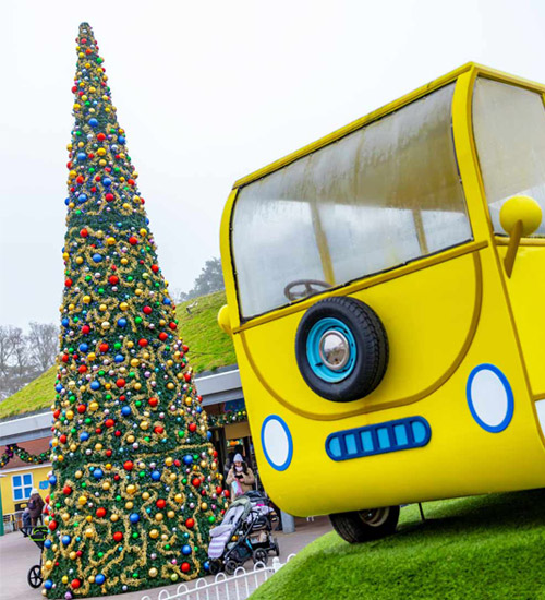 Giant Christmas tree beside yellow campervan during Christmas at Peppa Pig World