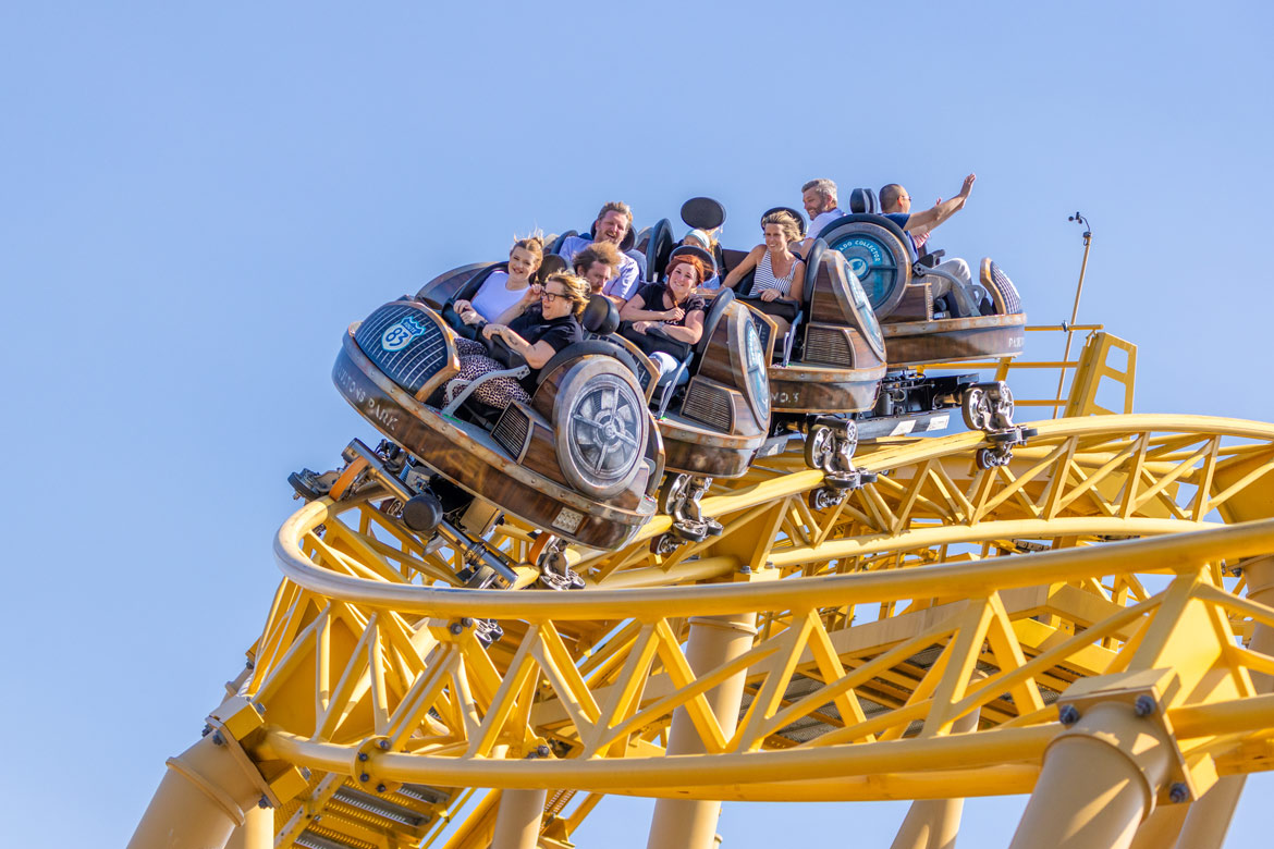 Riders enjoying Storm Chaser as the roller coaster car descends the yellow track at Paultons Park.
