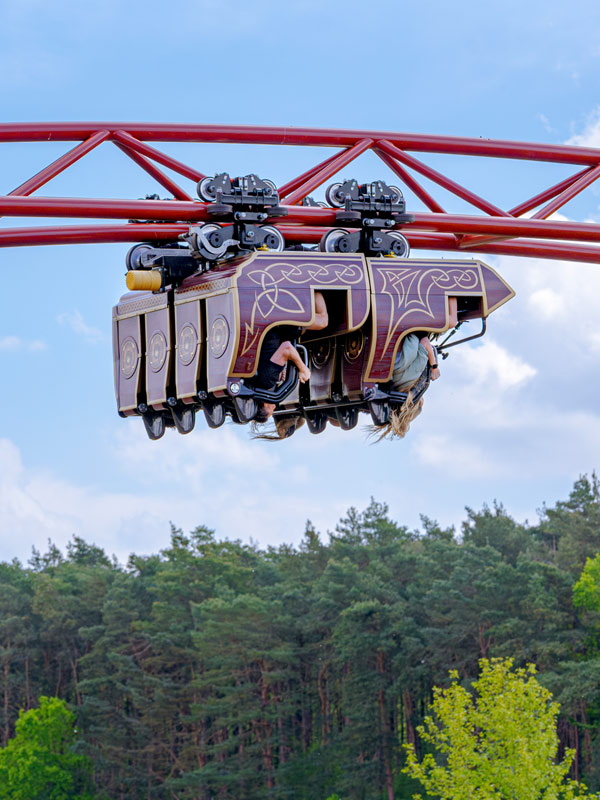 Riders enjoying Drakon rollercoaster at Paultons Park as the train passes beneath the red track