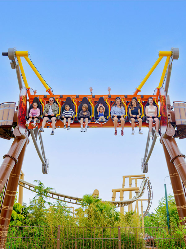 Riders seated on Vild Swing at Paultons Park, suspended high above the Valgard themed ride area.