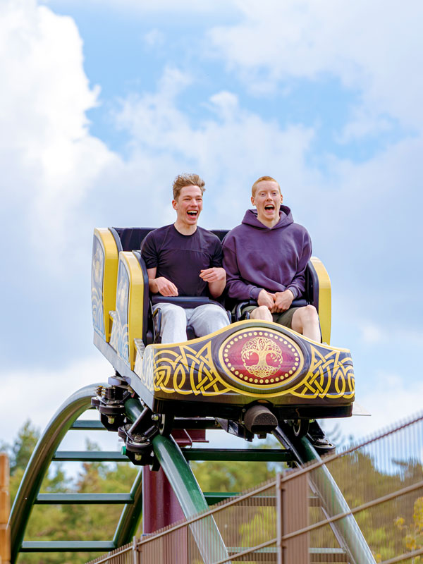 Two riders enjoying Raven Coaster in Valgard at Paultons Park against a blue sky.