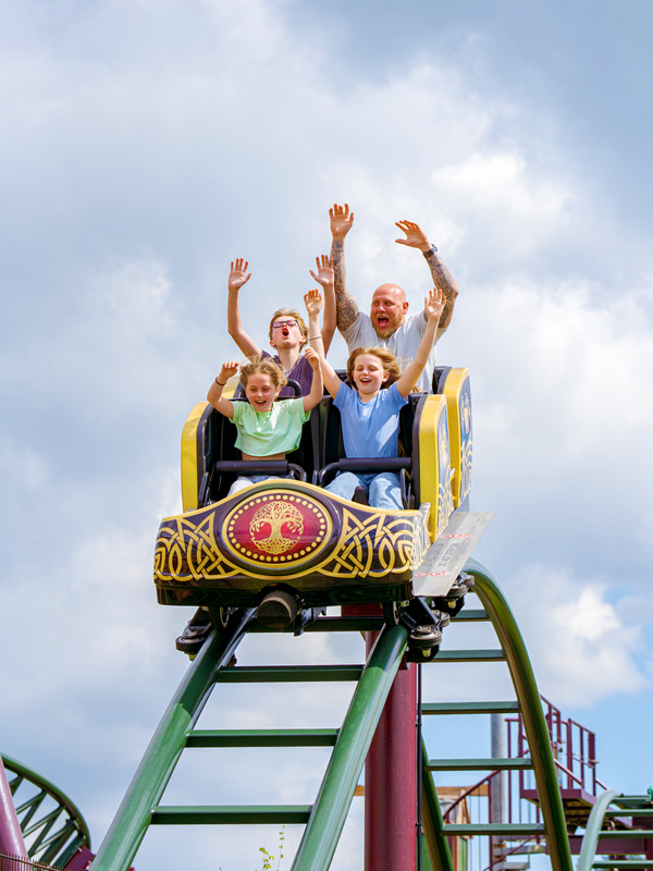 Family with hands in the air riding Raven Coaster in Valgard at Paultons Park.